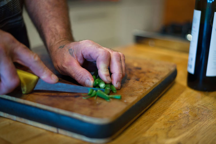 Cropped image of man cutting vegetable on cutting board