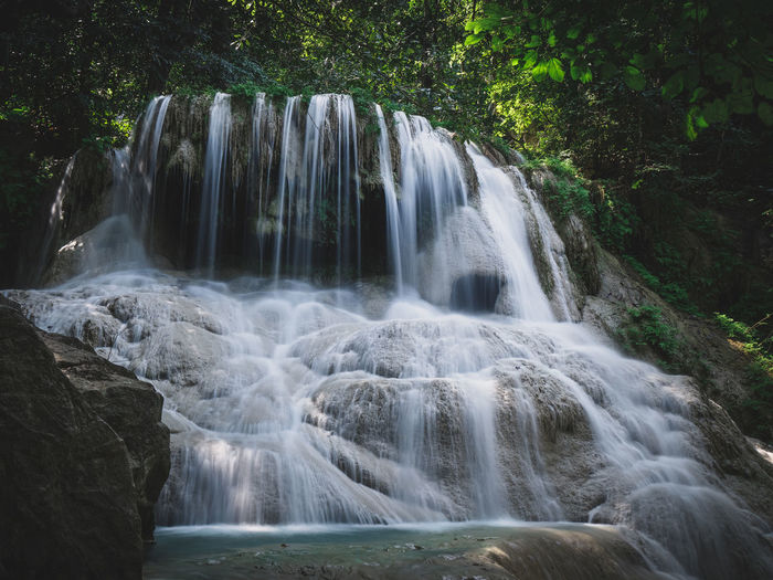 Epic paradise waterfall smooth flowing stream in rainforest. erawan falls, kanchanaburi, thailand.