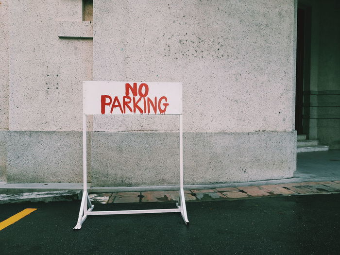 No parking sign on road against building wall