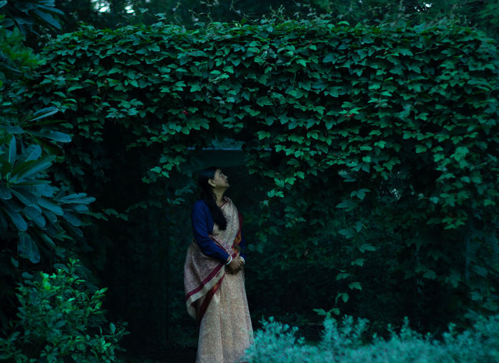 Woman in sari standing against plants