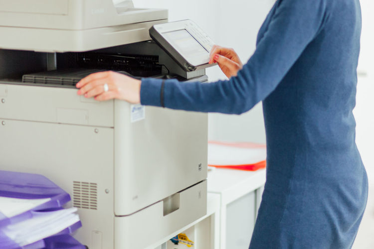 Side view midsection of woman using photocopier in office