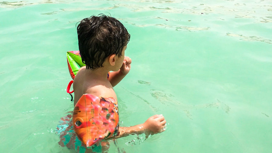 High angle view of boy with water wings swimming in sea