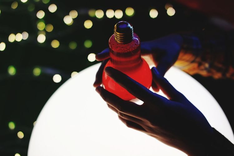 Close-up of hand holding illuminated bottle