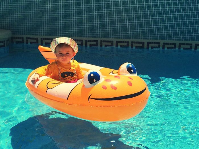 Portrait of cute baby girl sitting in inflatable on swimming pool