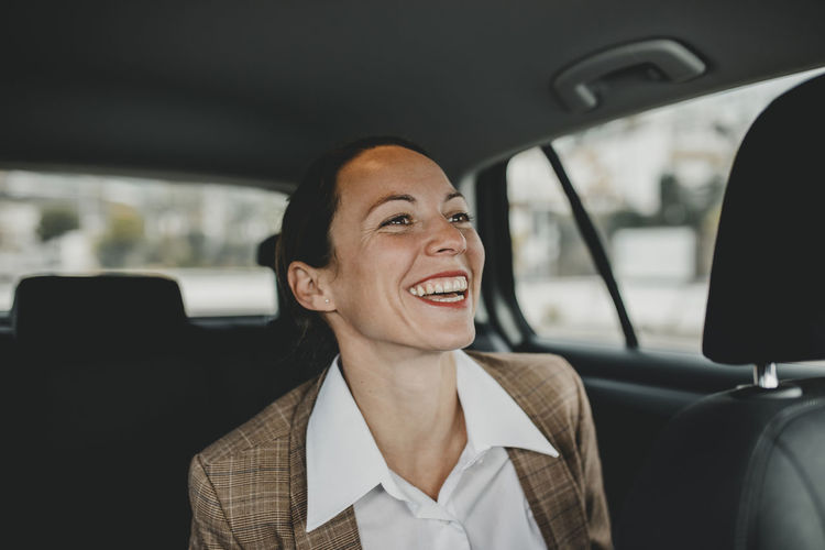 Cheerful female professional sitting on back seat while traveling in taxi