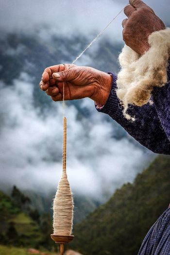 Cropped hands holding spool against mountains