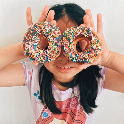 High angle view of girl holding doughnuts in front of her face