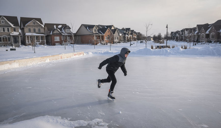 Teenage boy skating on an outdoor neighbourhood ice rink.