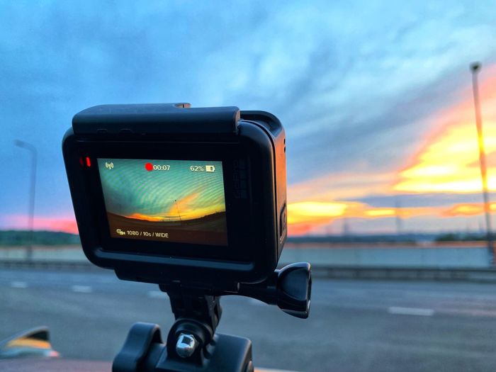 Close-up of camera on road against sky during sunset