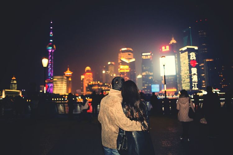 People standing next to illuminated buildings