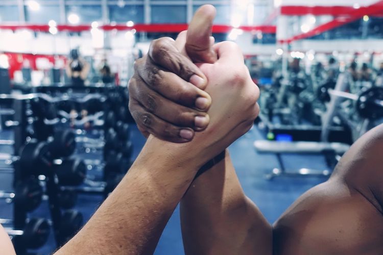 Cropped hands of men arms wrestling at gym