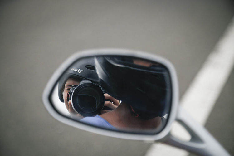 People reflecting on side-view mirror of motorcycle