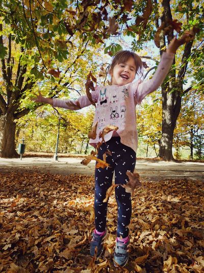 Full length of girl playing with autumn leaves