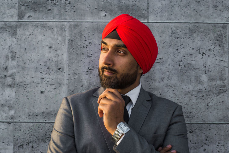 Smiling businessman wearing turban against wall