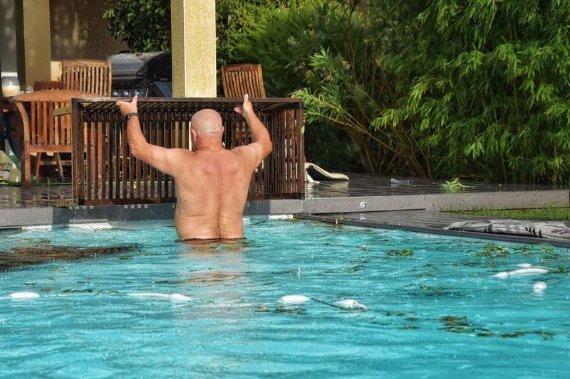 Rear view of shirtless man in swimming pool