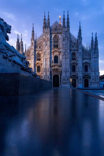 Dark architecture image of the duomo cathedral in milano italy. view with the lion statue