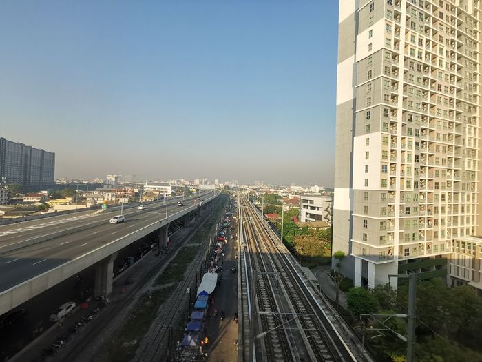 High angle view of railroad tracks amidst buildings against clear sky