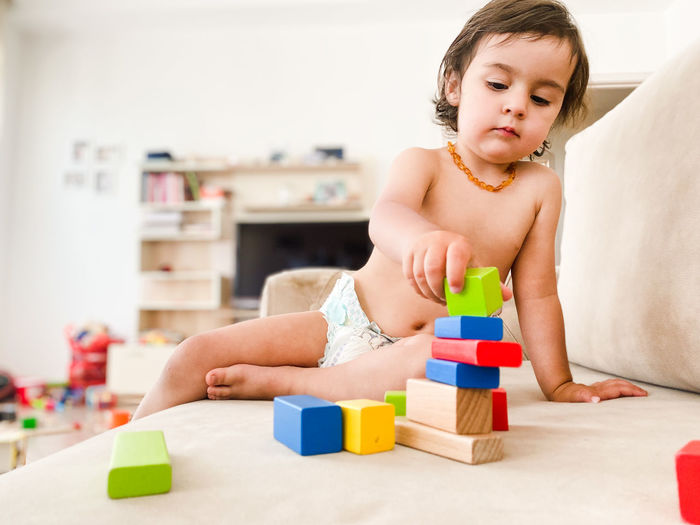 Toddler boy playing with wooden toy blocks at home