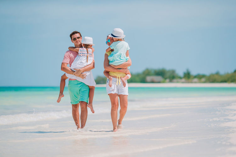 Full length of cheerful family walking on beach