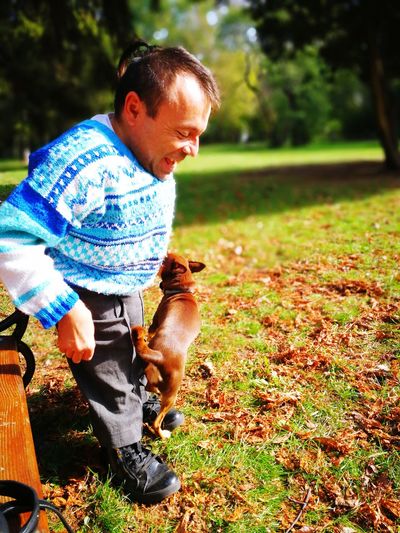 Smiling mature man playing with dog at park