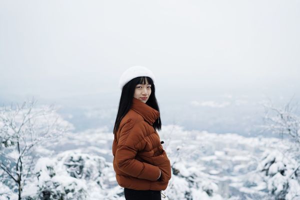 Portrait of woman standing on snow against sky