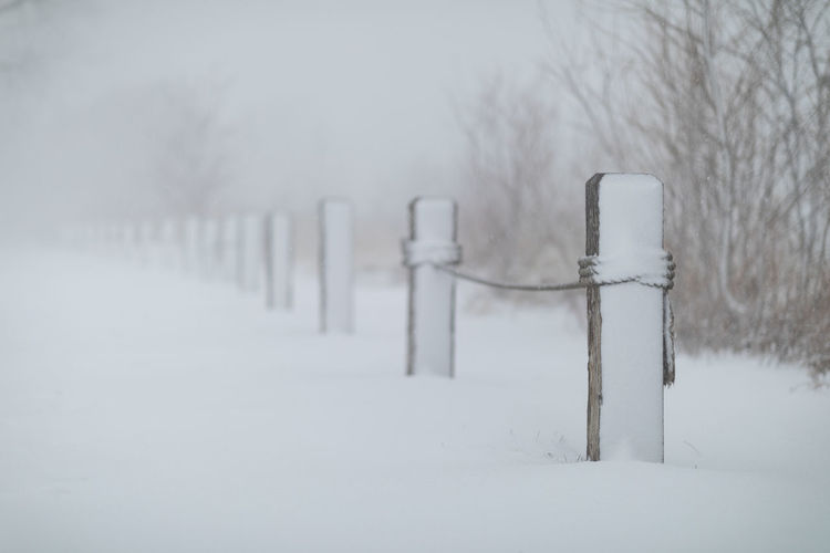 Snow covered wooden post on field during winter