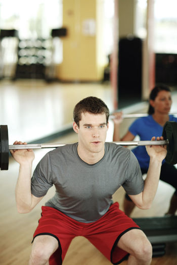 Determined male athlete lifting barbell in gym