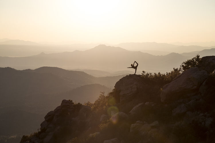 Silhouette person on mountain against sky during sunset
