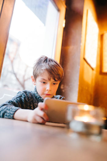 Close-up of boy playing with phone on table