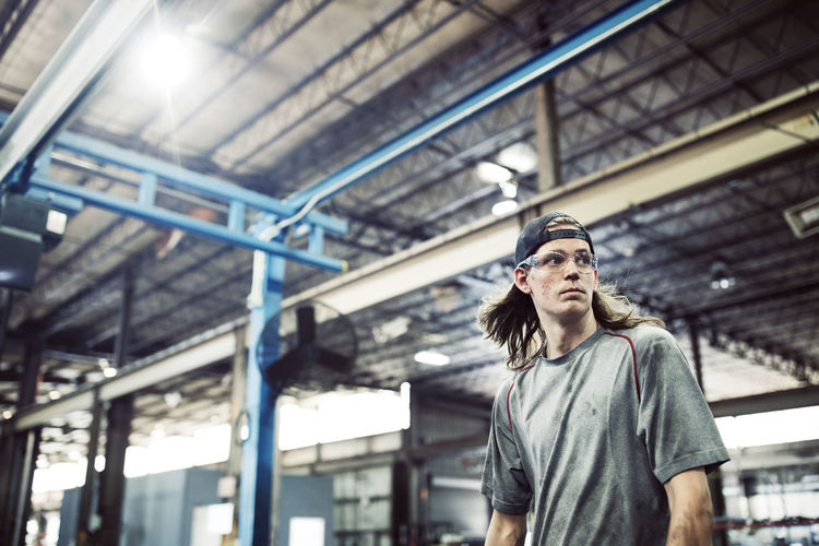Worker looking away while standing in steel factory