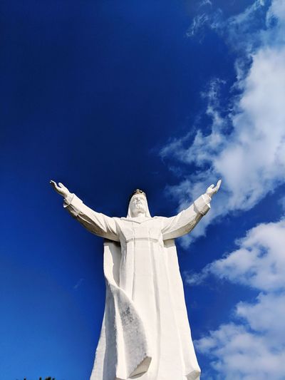Low angle view of statue of jesus against blue sky