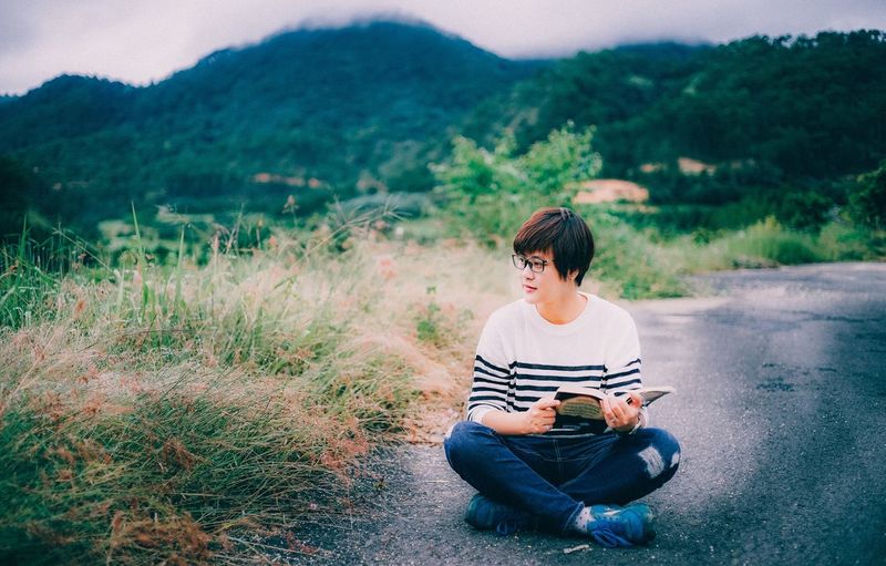 Young woman sitting on mountain against trees