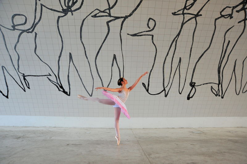 Full length of woman dancing on pink wall