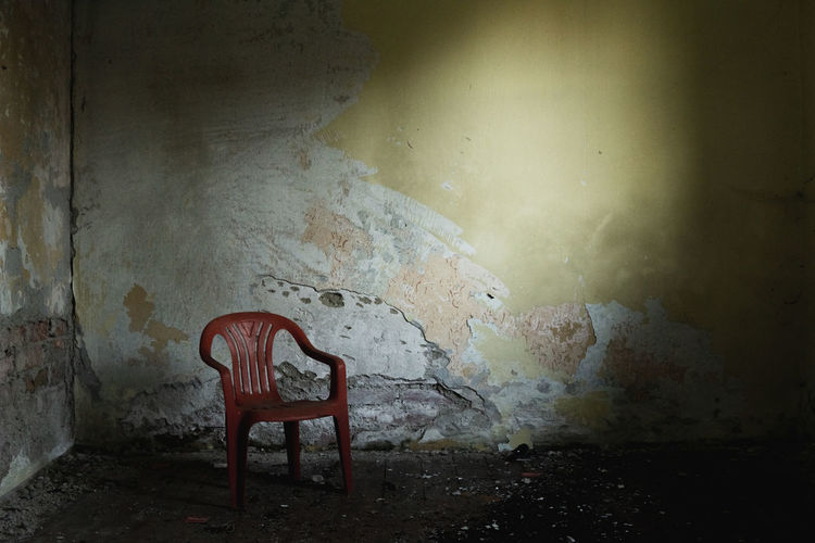 Empty chairs against wall in abandoned building