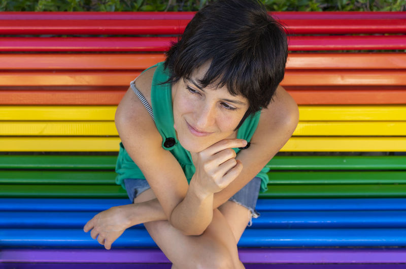 Portrait of a woman sitting on multi colored bench
