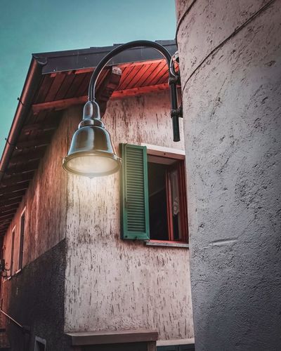 Low angle view of lamp hanging on wall of building