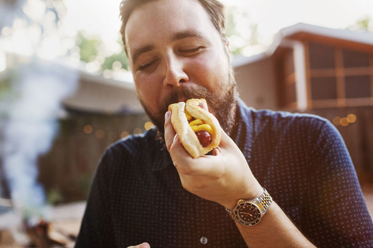 Man eating hot dog at yard