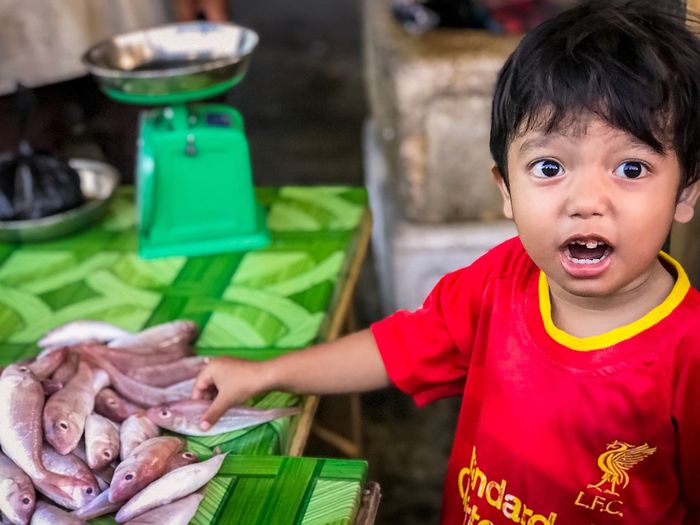 Close-up cute boy holding fish at market stall