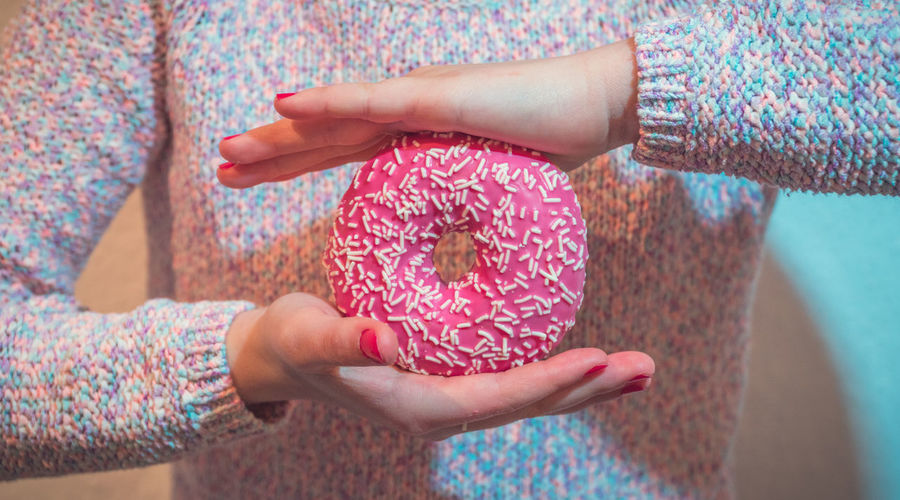 Midsection of woman holding donut at home