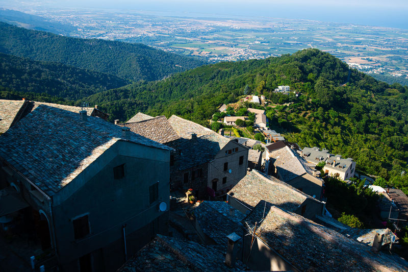 High angle view on a corsican village in the mountains with forest and sea in the background