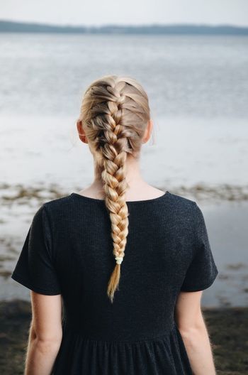 Rear view of young woman with braided hair standing on beach
