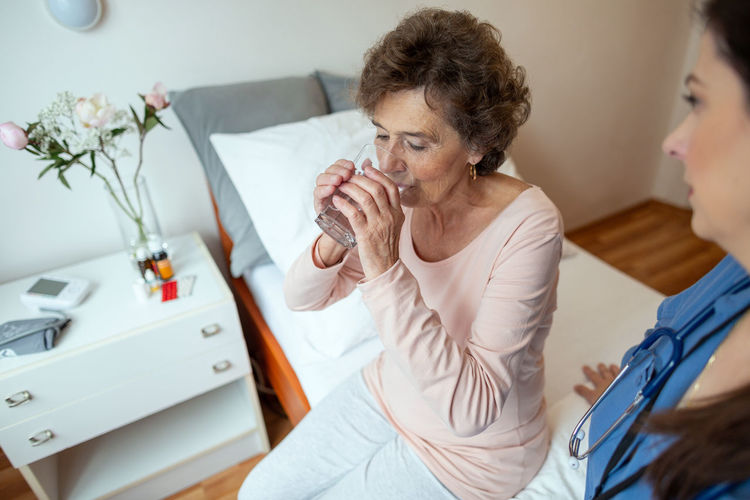 Doctor looking at patient drinking water in hospital