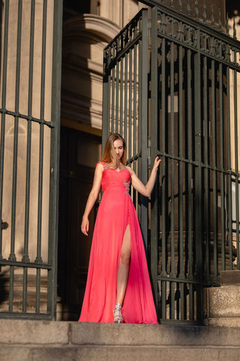 Low angle view of beautiful woman in pink evening gown standing at doorway