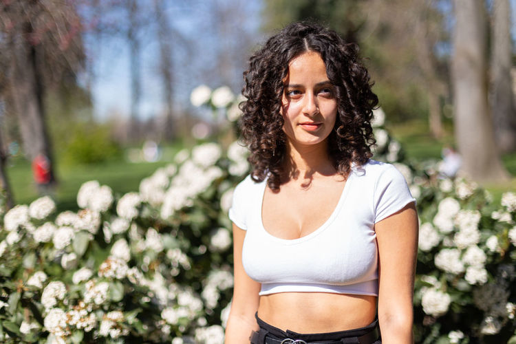 Portrait of young woman standing against trees