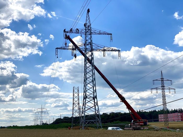 Low angle view of crane on field against sky