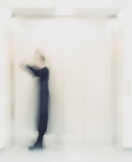 Defocused image of man standing against wall