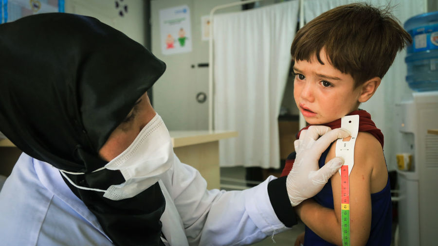 Doctor wearing mask examining patient at clinic