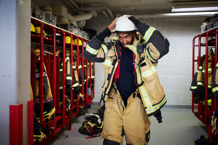 Mid adult firefighter wearing work helmet in locker room at fire station