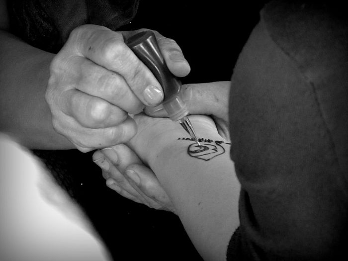 Close-up of artist applying henna tattoo on hand