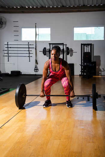 Determined woman lifting weights at the gym. squat